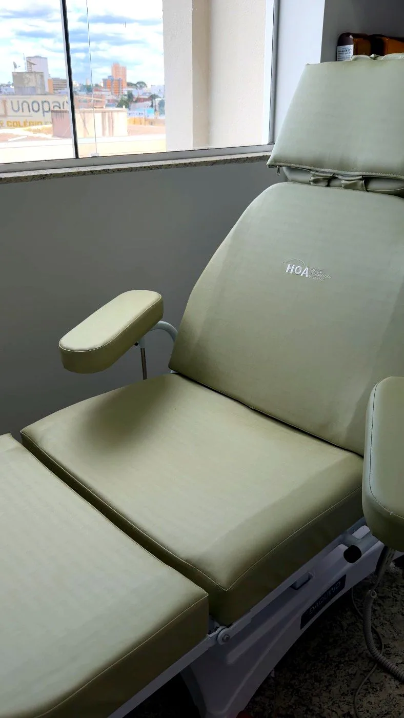Sala de procedimentos da HOA Aesthetic, com maca reclinável em couro claro gravada com a marca HOA