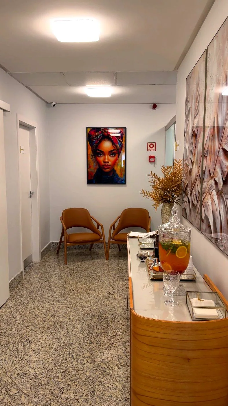 Corredor de atendimento da HOA Aesthetic, com poltronas, quadros e estação de cortesia