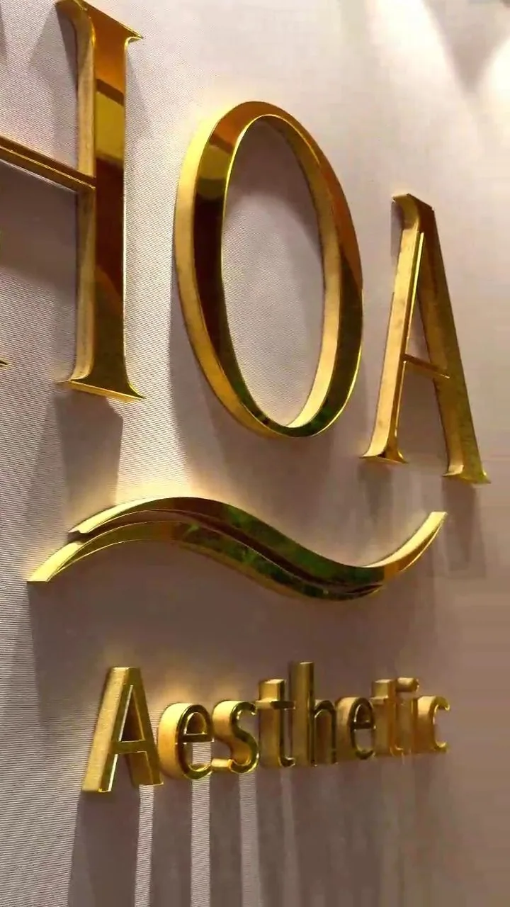 Letreiro dourado da HOA Aesthetic no lounge, em detalhe